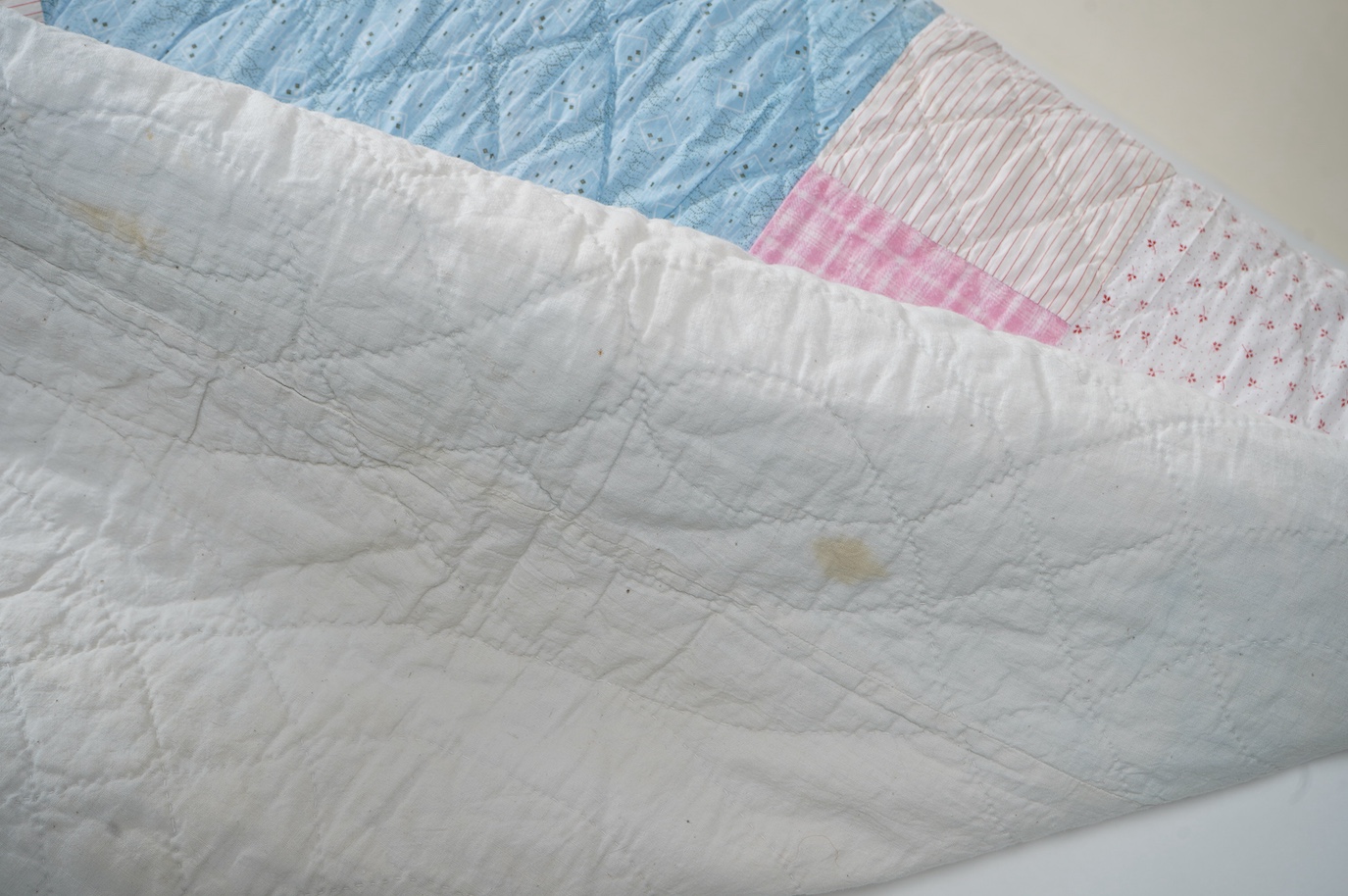 A 1900-1910 English, possibly north country hand quilted bedcover. Designed with a large central medallion, hand quilted using mostly pastel patterned and plain cottons and feature red and black cottons as highlights, ba